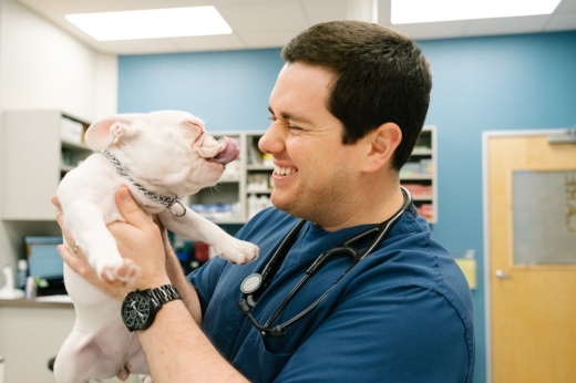 a man smiles as he holds a small dog