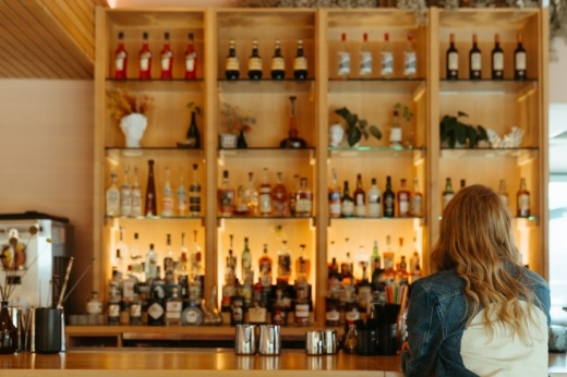 A person has their back toward the camera while looking at the bar wall.