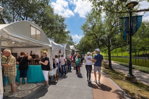 People walk down the Waterway alongside art exhibits.