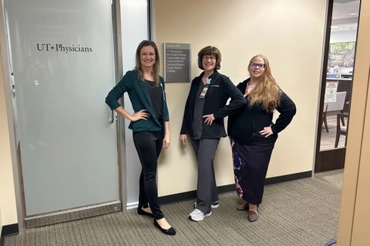 three women stand in front of a door at an office