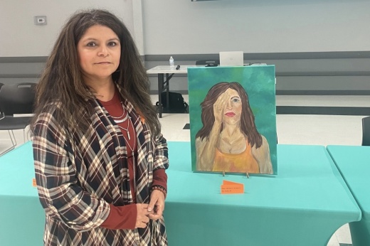 An artist stands with their painting as part of an art exhibit put on by Turning Point in Webster. (Courtesy Turning Point)