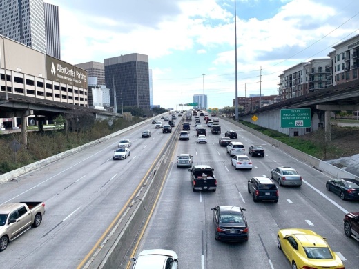 cars drive on a highway through a downtown cityscape