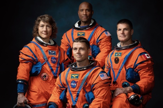 four astronauts in orange space suits