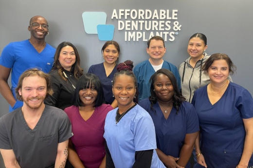 Group of men and women wearing scrubs in front of Affordable Dentures & Implants sign.
