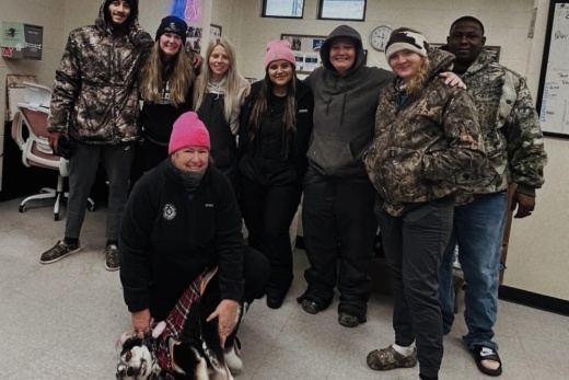 A group of shelter volunteers and workers pose for a photo with a dog.