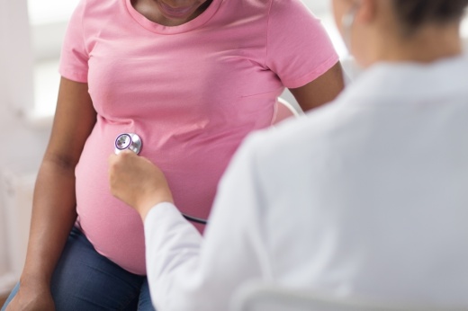 A pregnant woman receives a check-up from a physician.