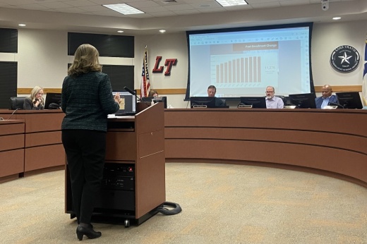 A woman presents behind a podium to the Lake Travis ISD board of trustees