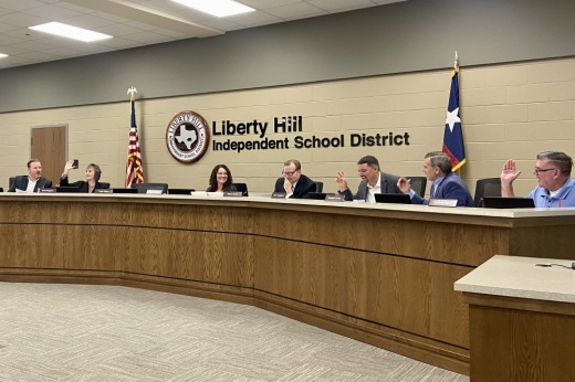 The Liberty Hill ISD board of trustees raise their hand to take a vote