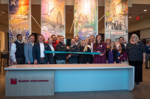 A large group of people stand with a ribbon for a ribbon-cutting ceremony of the Wilsonart showroom in Pflugerville.