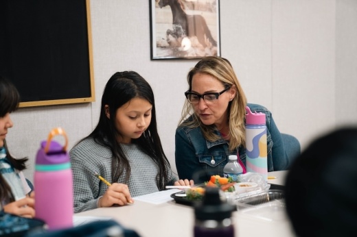 teacher sits at a table with a student