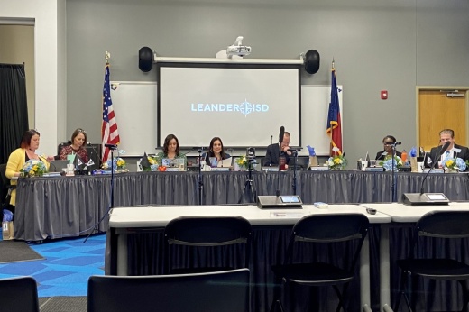The Leander ISD board of trustees sit behind a long table and prepare to take a vote
