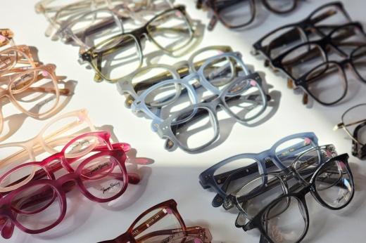 A close up of a white table covered in glasses of various colors.