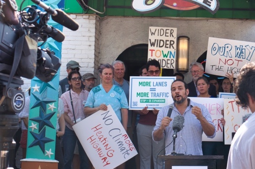 A group of people holding signs that protest TxDOT's I-35 expansion project