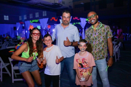 five people posed with glow sticks at a glow-in-the-dark party