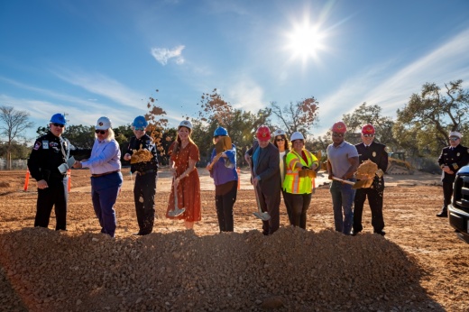 Men and women line up with shovels next to each other and shovel dirt pile