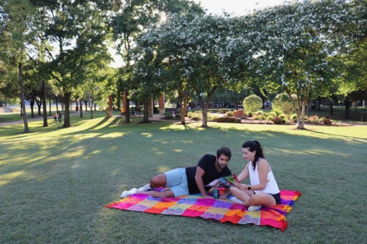 The photo shows two people reading on a blanket at Wussow Park.