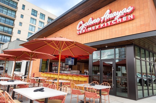 tables and chairs sit outside under an umbrella next to a cyclone anaya's building
