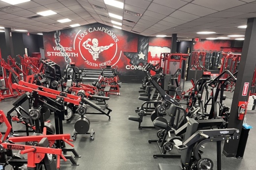 A room is filled with black and red equipment. A back wall is painted red with the Los Campeones Austin North logo and more in white.