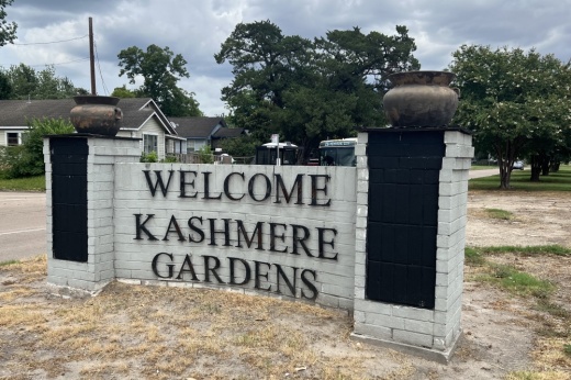 a sign in an open grassy area welcoming people to kashmere gardens