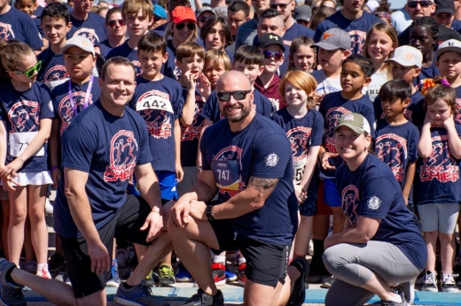 The Georgetown police chief and city manager pose and smile in front of a crowd of children.