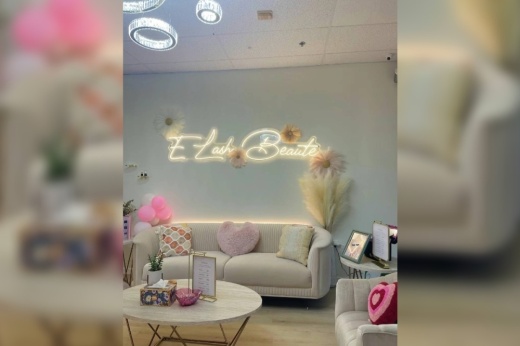 the interior of E lash Beauté, which shows a neon sign of the name on the wall and couches with heart pillows