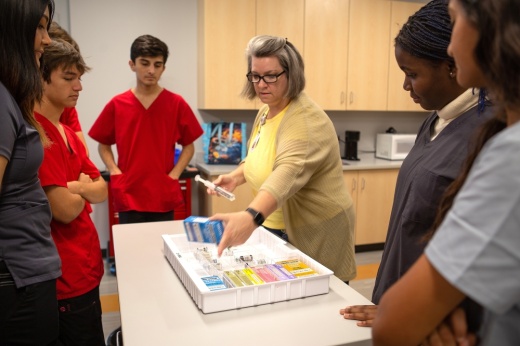 The photo shows students learning medical techniques.