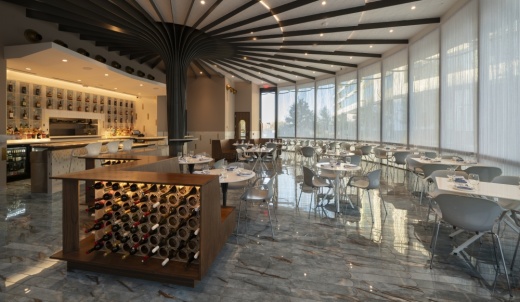 The interior of a circular building with a bar, tables and floor-to-ceiling glass windows
