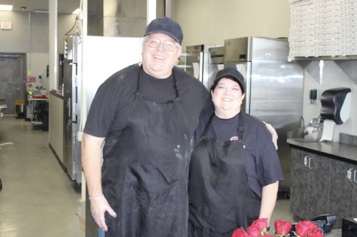 Picture of two people standing at the front counter of their pizza restaurant.