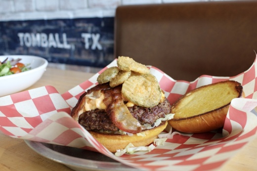 A burger on an open bun placed on checkered paper
