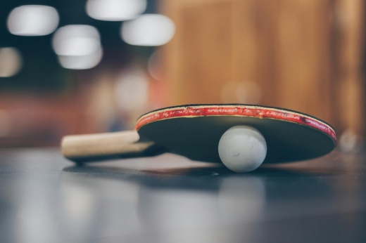 A ping pong paddle is shown on top of a ping pong ball.