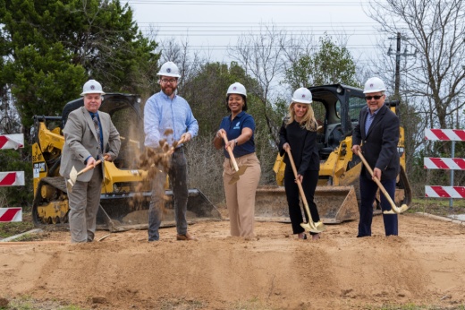 People holding shovels and wearing hard hats at a ground breaking ceremony