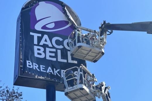 Workers on cranes change the Taco Bell sign