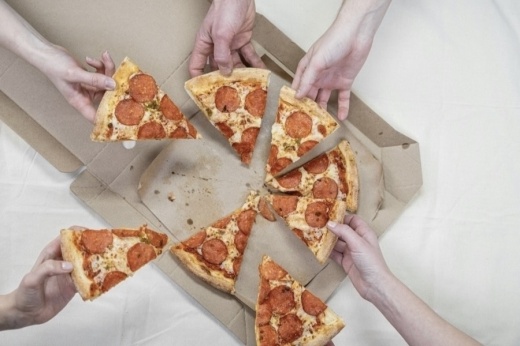 Picture of people taking pizza from a box.