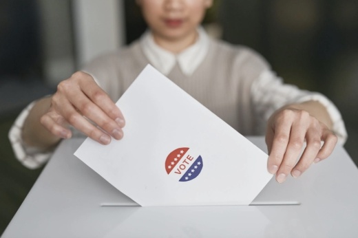 A person dropping a ballot in a box.