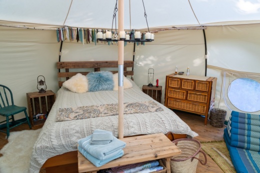 The inside of a glamping tent surrounded by a forest.