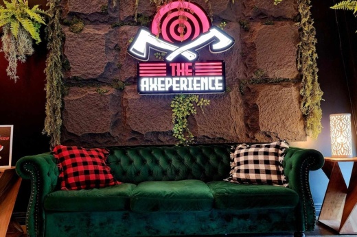 A green couch sitting below a sign that says The Axeperience