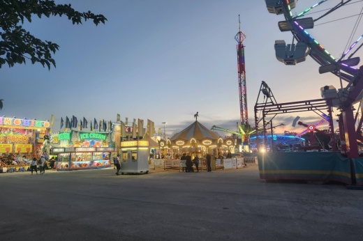 Carnival rides and game booths at twilight.