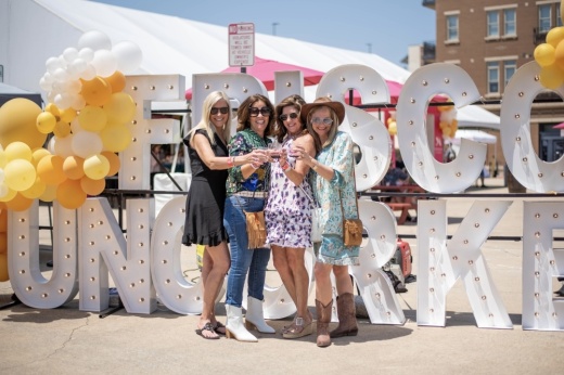 Four people standing in front of the Frisco Uncorked sign.