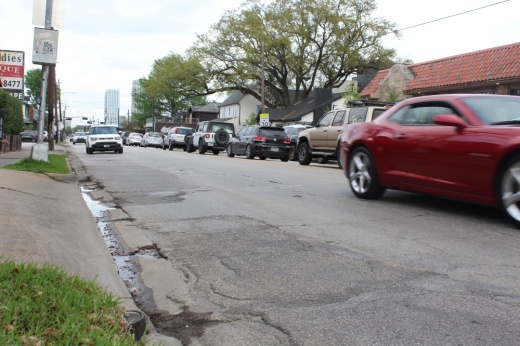 cars drive on a road with cracked pavement