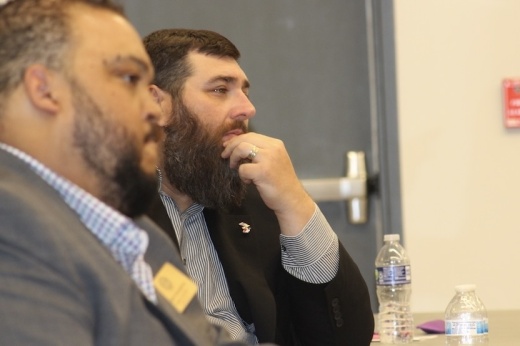 Picture of two men listening at a table during a meeting.