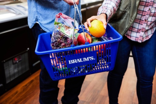People holding a Braum's shopping basket with produce in it.