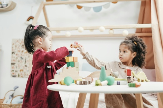 two small girls play with blocks at a table