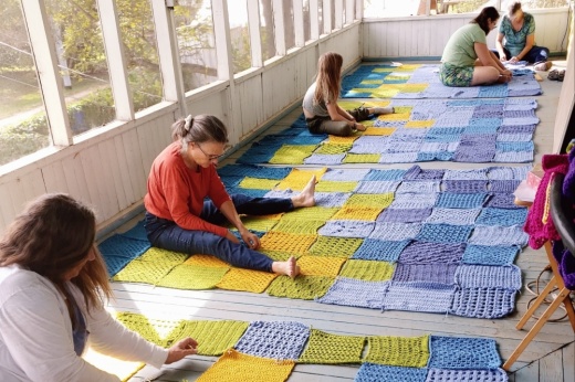 People sit on the floor working on patches.