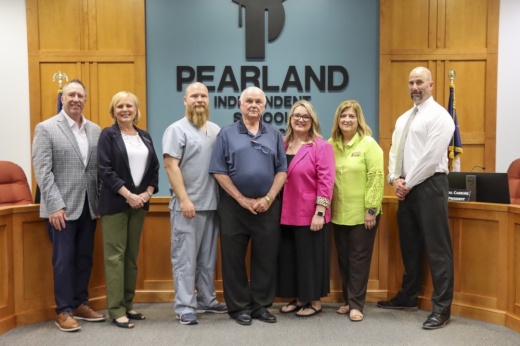 seven people pose together in front of a board meeting dais