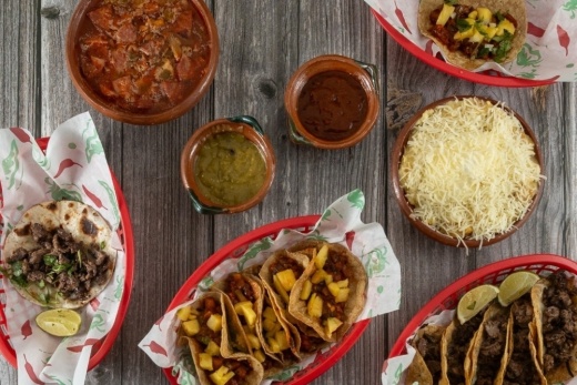 A table is filled with Mexican food like tacos and salsas.