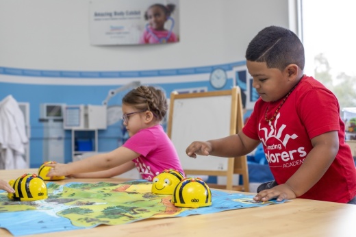 Two kids are playing with toys on a table at an Amazing Explorers Academy preschool.
