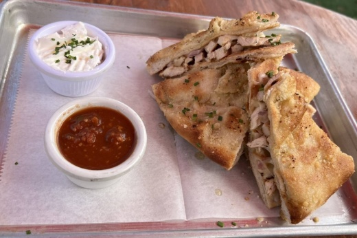 Triangular hand-held food items with two dipping sauces.