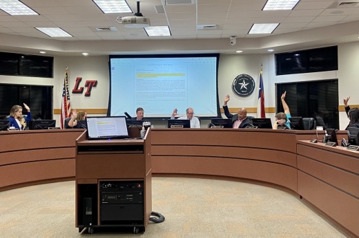 The board of trustees raise their hands to take a vote
