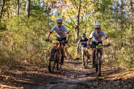 three people riding bikes in the forest