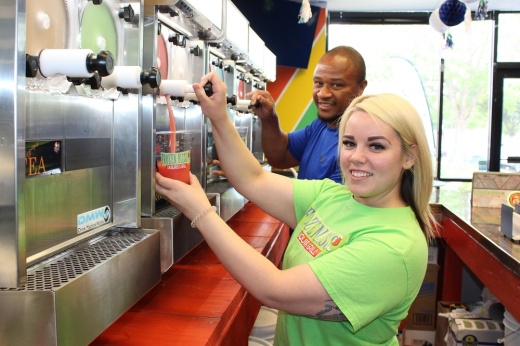 Female in foreground, male in background dispensing frozen drinks from drink machines